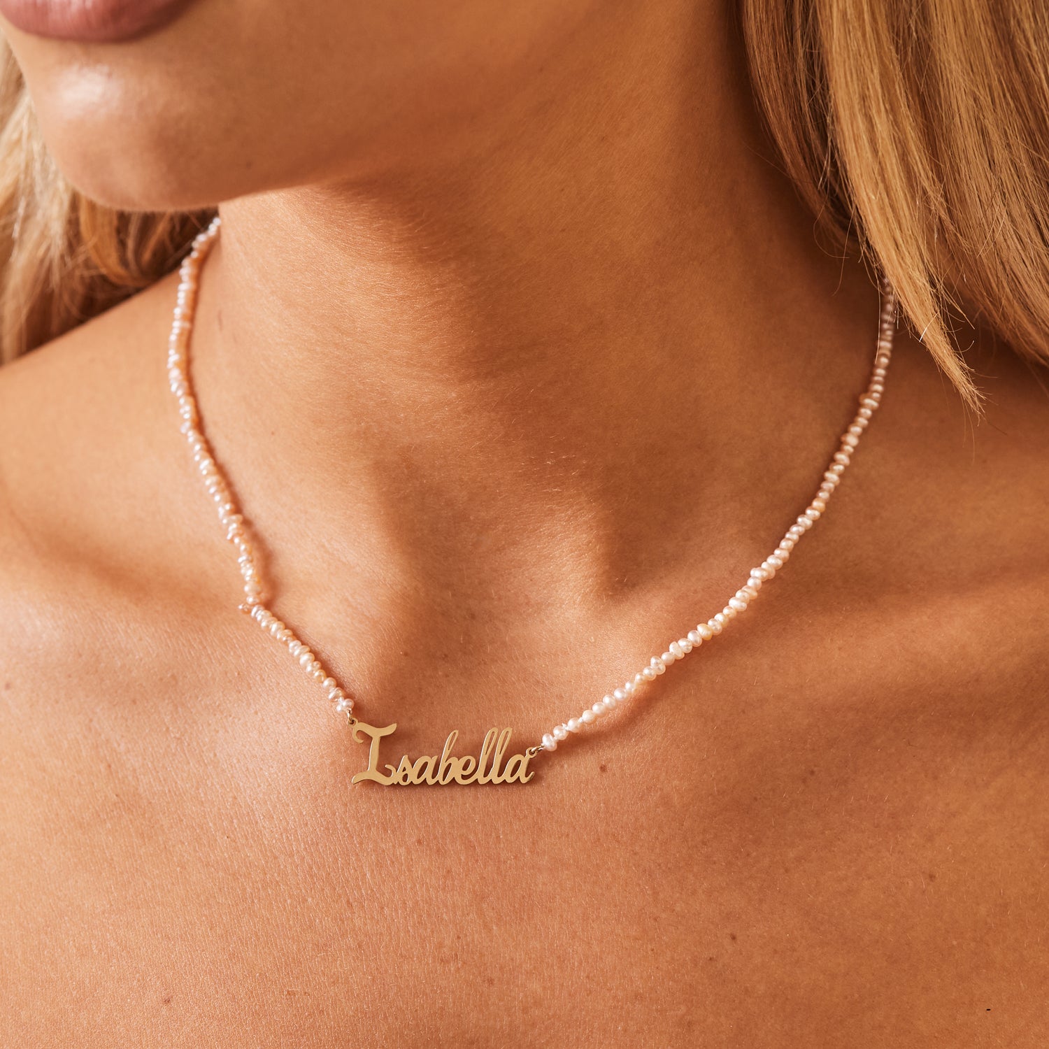 Close up of freshwater mini pink pearl necklace on neck with 14k solid gold nameplate.