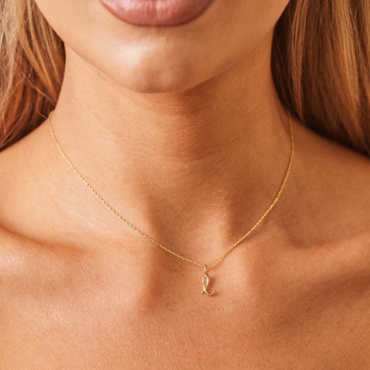 Close up of model's neck with dainty 14k solid gold cable chain and Mini Letter Charm. 14in chain falls in line with collarbone.