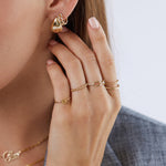 14K gold dome eternity ring worn on hand close up stackable fine jewelry chunky earrings chunky rings dainty rings