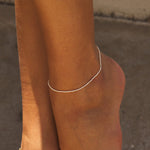 Model wearing dainty pearl anklet with white pearls and 14k gold on one ankle.
