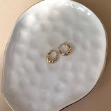 Croissant hoop earrings in 14k yellow gold flat lay on white plate.