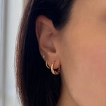 Model wearing croissaint hoop earrings in 14k solid gold on 1st piercing, huggies on 2nd piercing, and diamond stud on 3rd piercing.