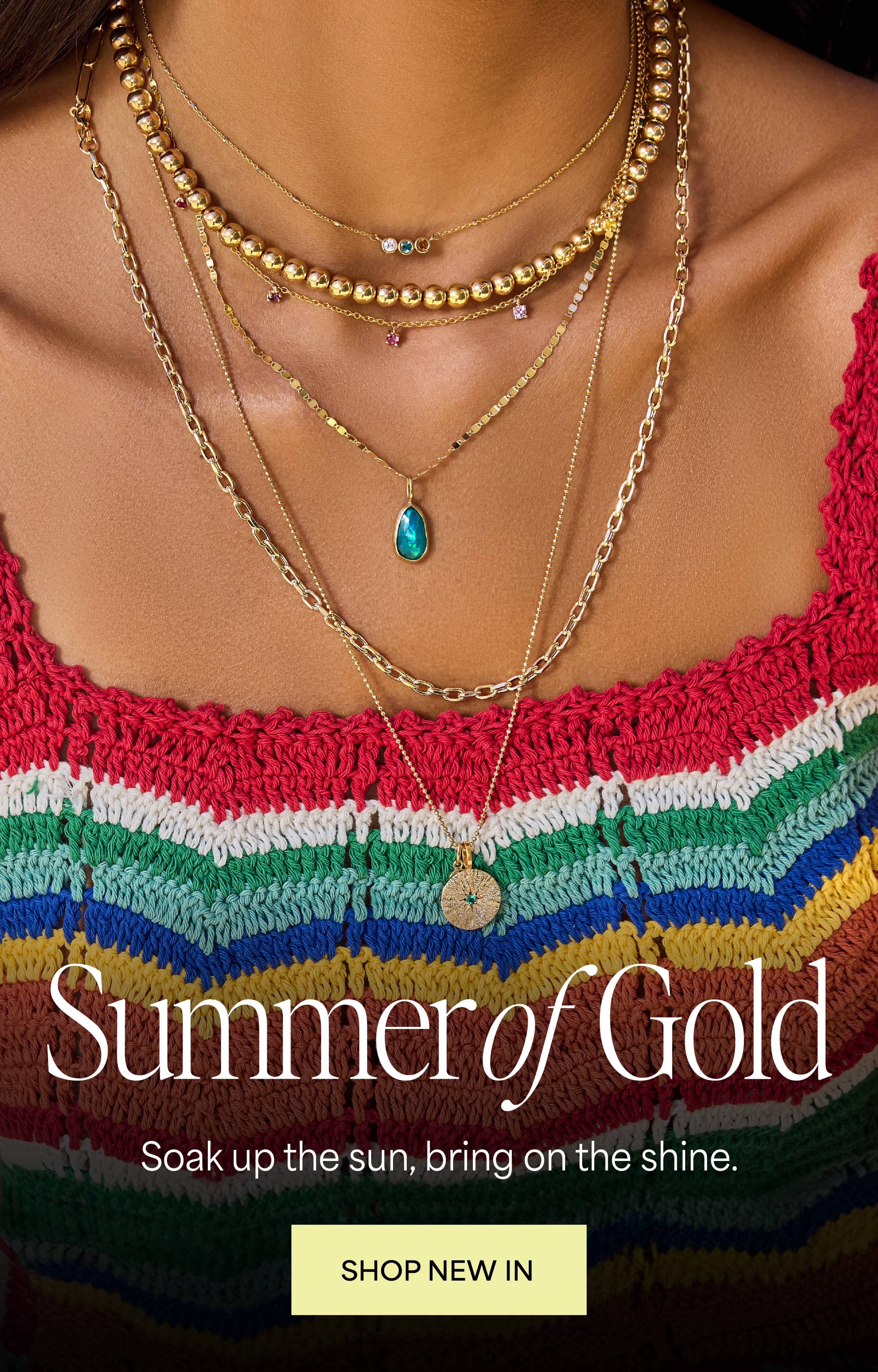 Model in 14K solid gold layered necklaces with gemstones, chains, charms, birthstones in colorful summer clothes.