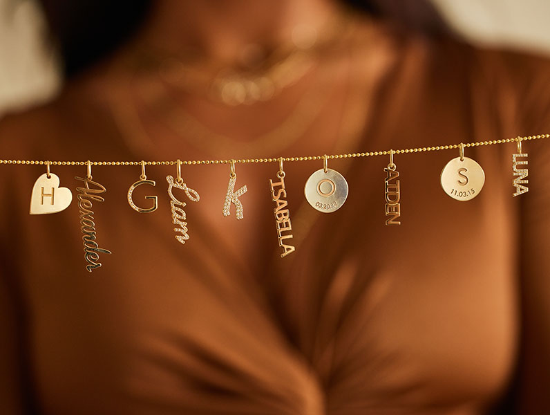 A chain with 14K solid gold personalized initial charms, name charms, engraved charms, pave charms.