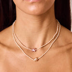 Model wearing two layered necklaces. One 16 inch mini pink freshwater pearl necklace with star pendant and one 18 inch mini white pearl stand with star pendant.