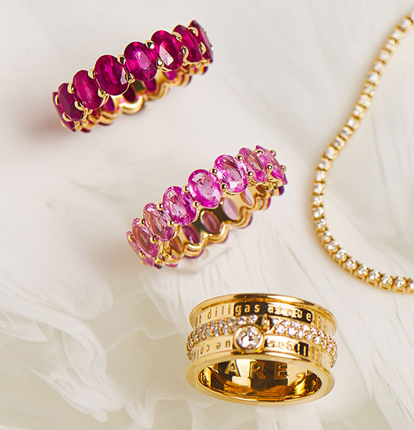 Product flat lay with 14K solid gold statement rings. Sapphire oval eternity rings, diamond statement ring, tennis bracelet with natural diamonds.