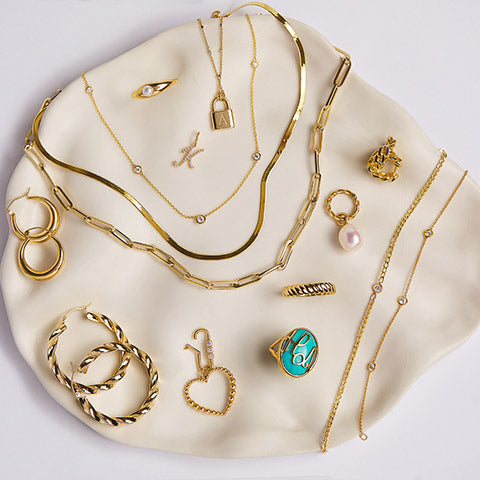 Flat lay of 14K solid gold bracelets, necklaces, rings, earrings, and charms.