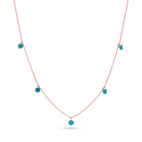 A 14k solid rose gold chain with 5 dainty turquoise beads draping off of it.