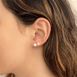 Model wearing 6mm pearl stud earring on first piercing and 4mm pearl stud earring on second piercing with 14k gold hoop on helix.